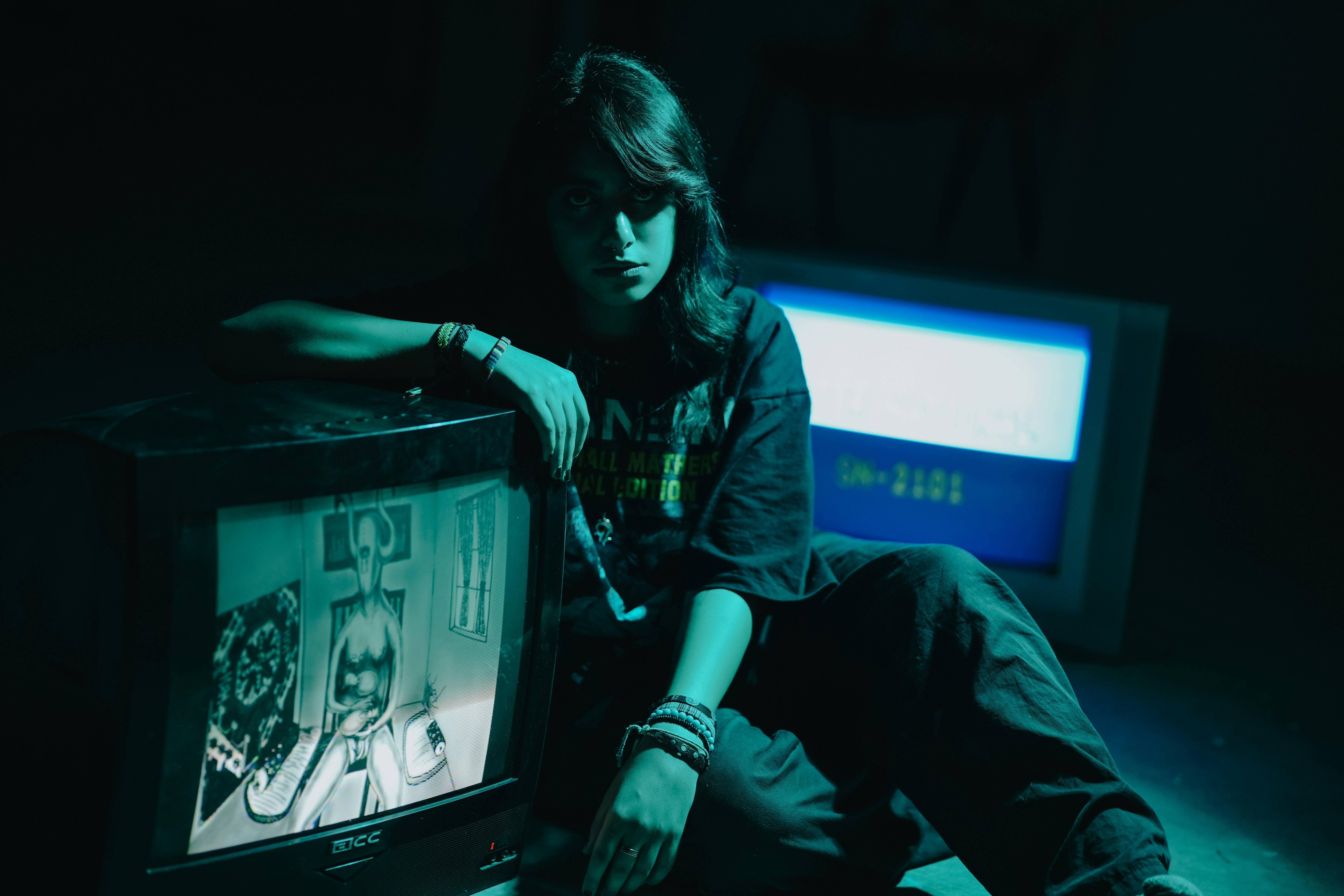 Teenager poses with vintage televisions in dark room